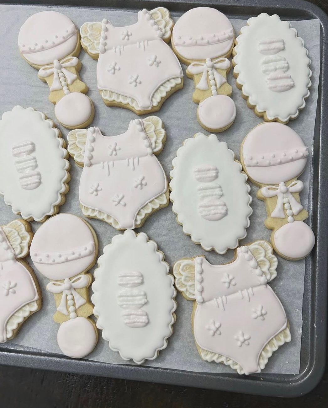 Pale pink and white baby shower cookies — onesies, rattles and decorated ovals