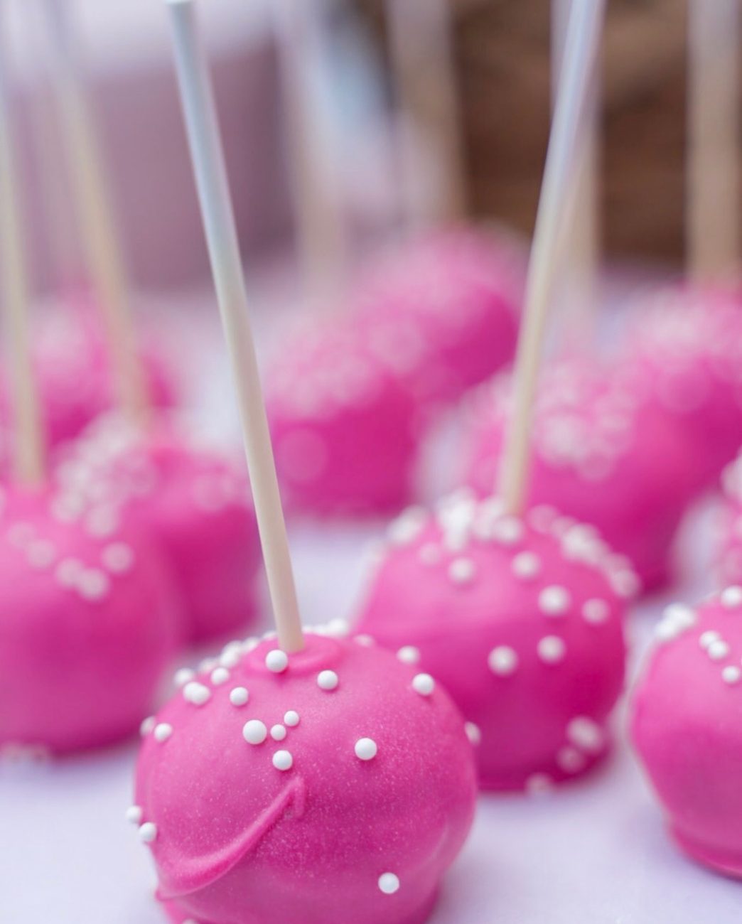 Bright pink cake pops with white nonpareil sprinkles