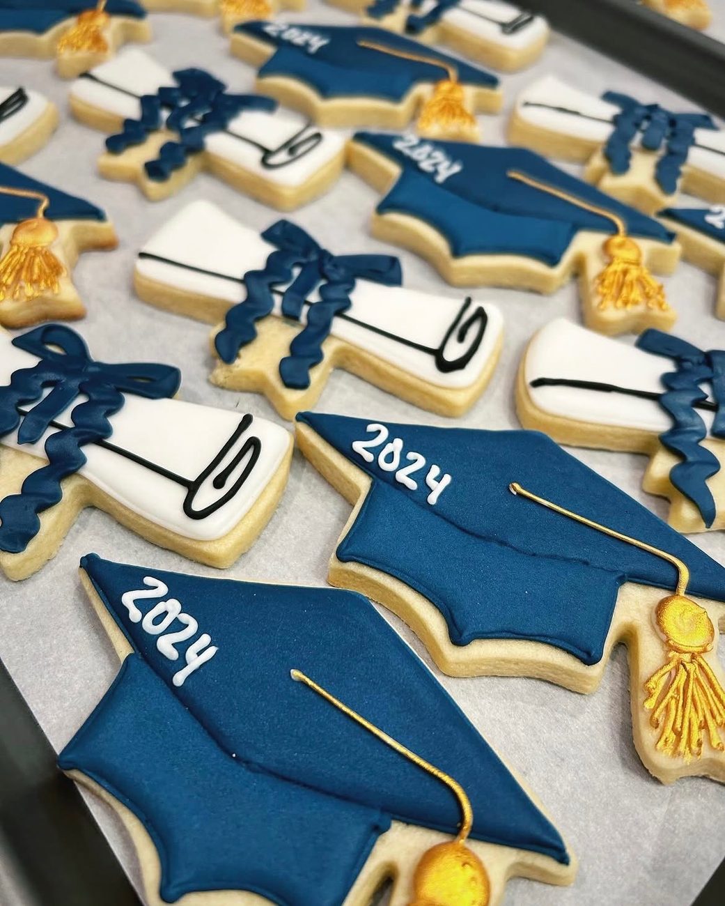 Navy and gold graduation cookies with 2024 caps, diplomas and tassels