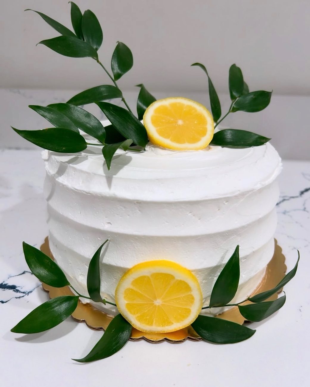 White buttercream cake finished with lemon slices and fresh greenery