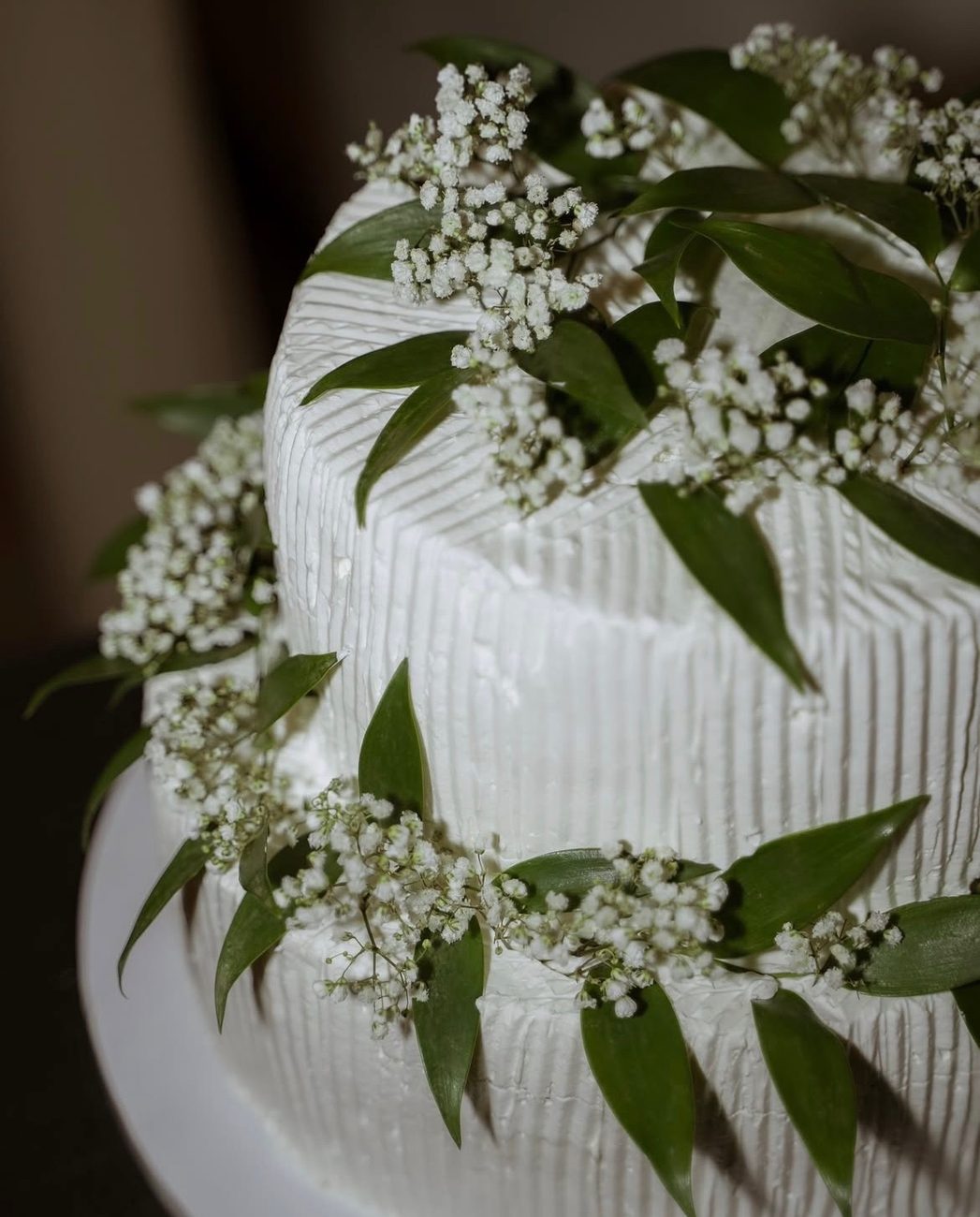 Two-tier white wedding cake with baby's breath and greenery
